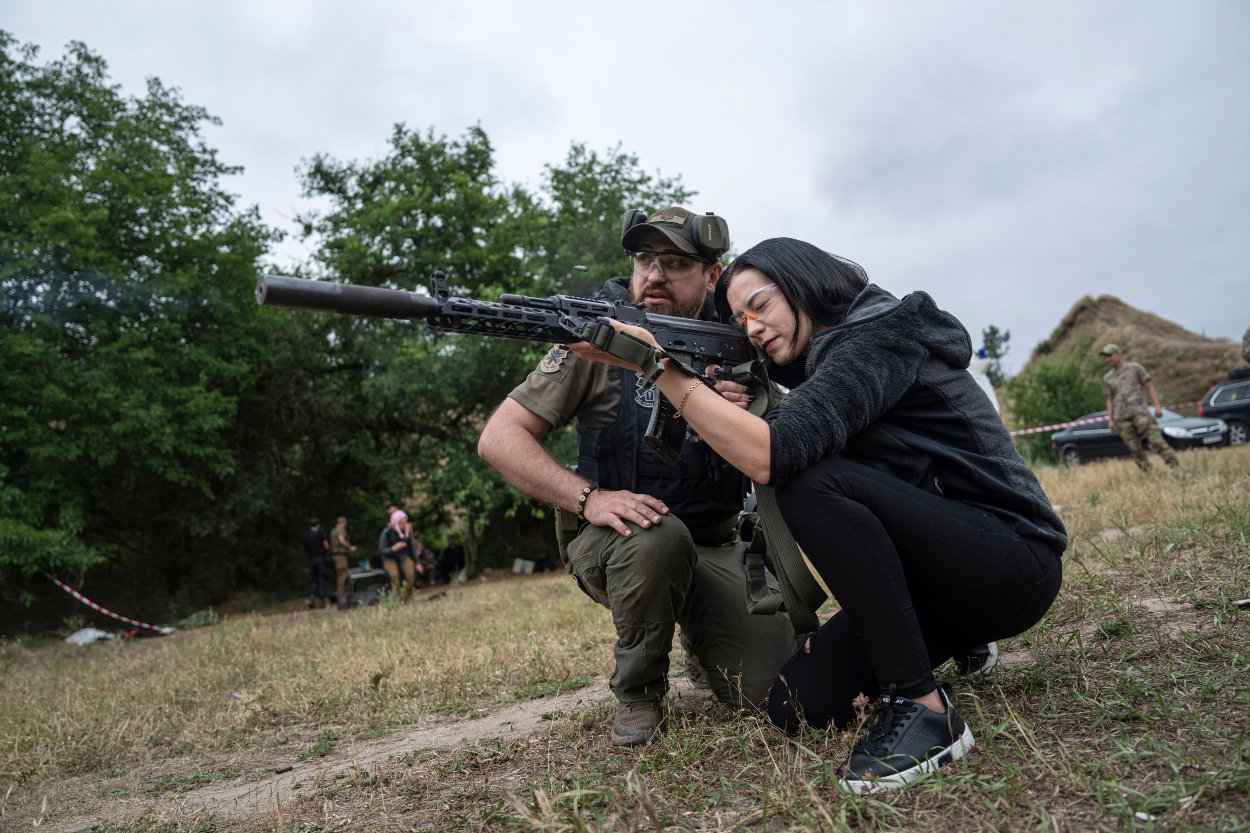 Žena strieľa z útočnej pušky AK-47 počas taktického výcviku civilistov pri priemyselnom meste Záporožie na juhovýchode Ukrajiny v nedeľu 9. júla 2023.