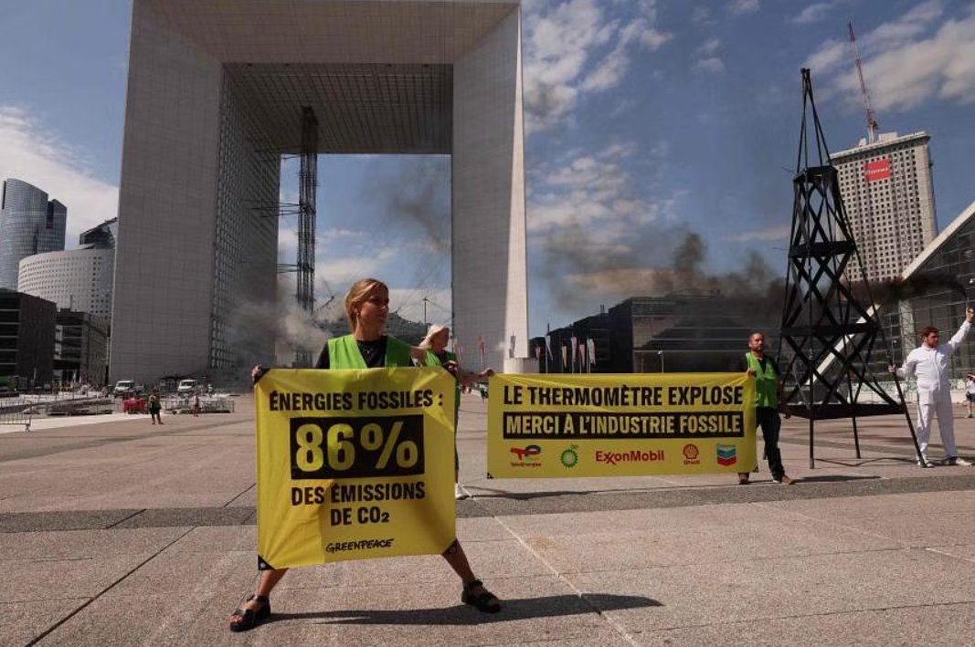 Členovia Greenpeace držia transparent s nápisom "Fosílne palivá: 86% emisií CO2" a "Termometer sa zvyšuje, vďaka priemyslu fosílnych palív" počas demonštrácie v La Defense, blízko Paríža, 22. augusta.