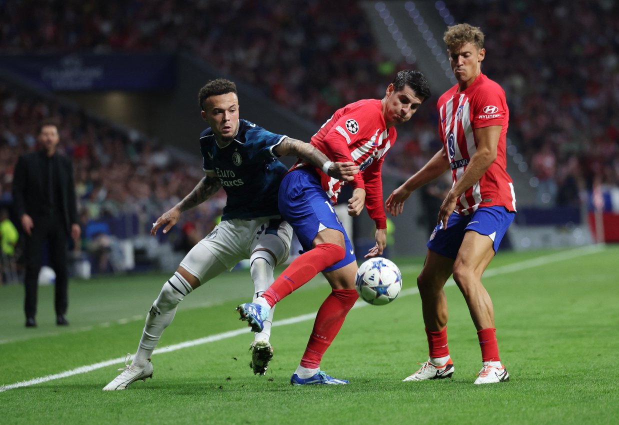 Hráč Feyenoordu Quilindschy Hartman v akcii s Alvarom Moratom z Atletica Madrid a Marcosom Llorente.