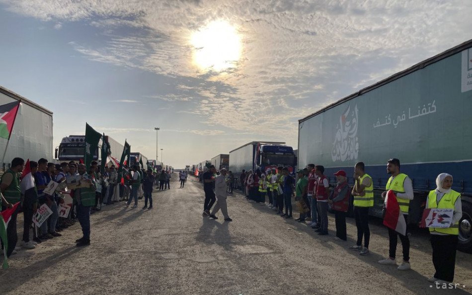 dobrovoľníci stoja pred kamiónmi humanitárnou pomocou pre Palestínčanov na hraničnom priechode medzi pásmom Gazy Egyptom Rafáhu