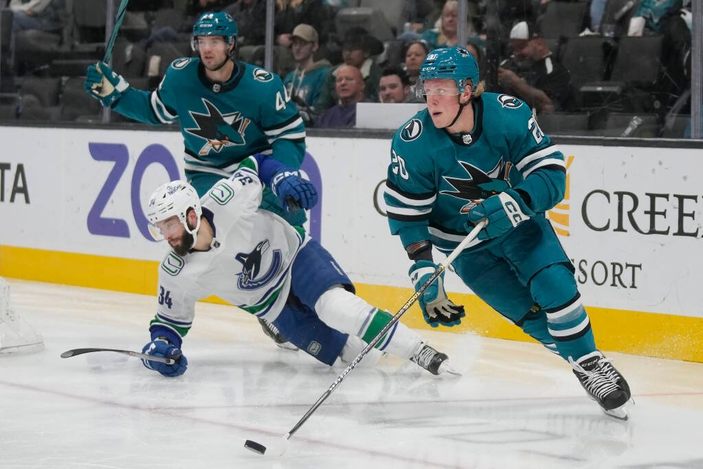 Ľavé krídlo Sharks Fabian Zetterlund (vpravo) korčuľuje s pukom pred obrancom Marcom-Edouardom Vlasicom a ľavým krídlom Vancouveru Canucks Phillipom Di Giuseppem počas druhej tretiny v San Jose, štvrtok 2. novembra 2023.