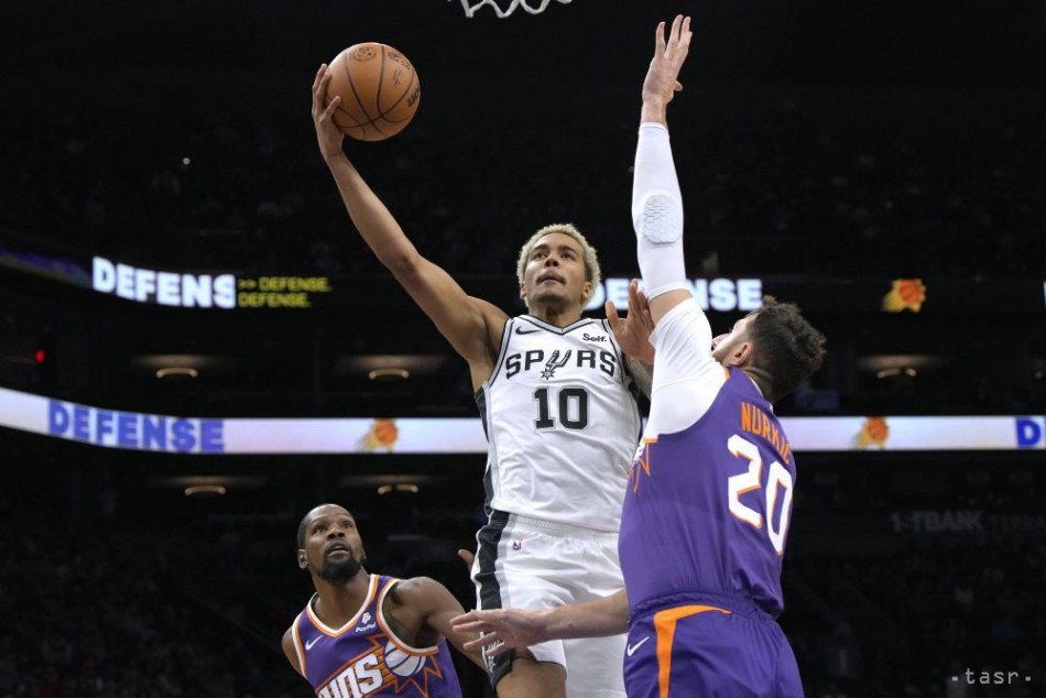 Útočník San Antonia Spurs Jeremy Sochan (10) strieľa spomedzi útočníka Phoenixu Suns Kevina Duranta a centra Jusufa Nurkiča (20) v druhom polčase basketbalového zápasu NBA vo štvrtok 2. novembra 2023 vo Phoenixe. 