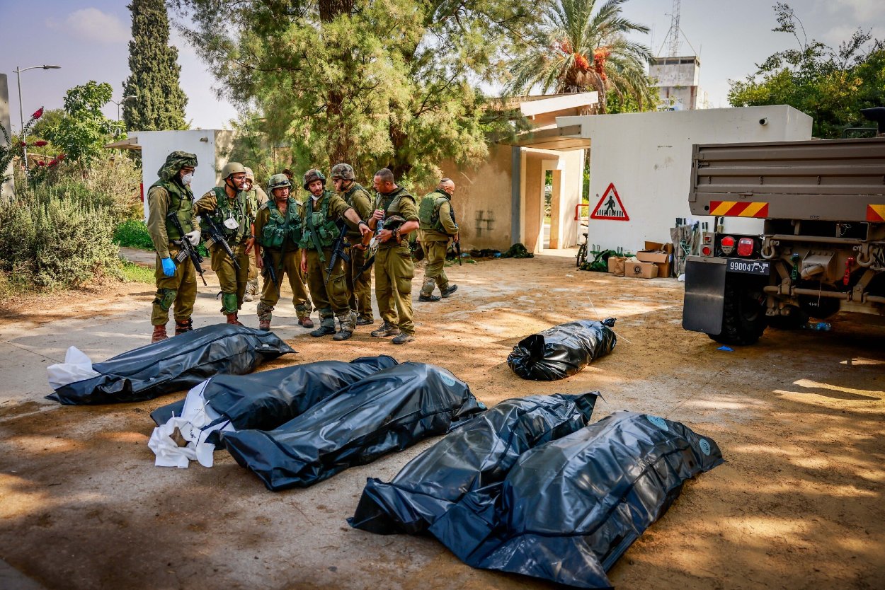 Izraelskí vojaci odstraňujú telá izraelských civilistov chladnokrvne zabitých teroristami z hnutia Hamas v kibuci Kfar Aza neďaleko izraelsko-gazskej hranice v južnom Izraeli, 10. októbra 2023.