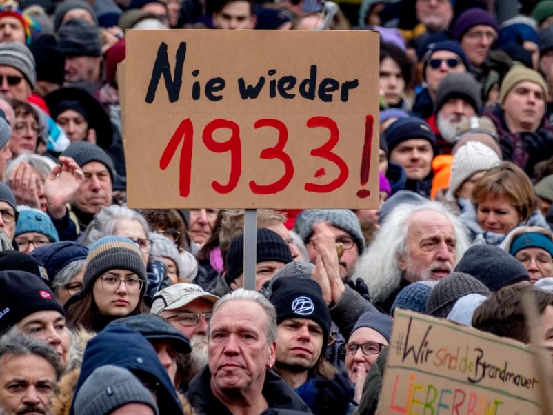 Ľudia sa zhromažďujú na proteste proti strane AfD a pravicovému extrémizmu vo Frankfurte nad Mohanom v Nemecku v sobotu 20. januára 2024. Na nápise je v preklade: „nikdy viac 1933!“.