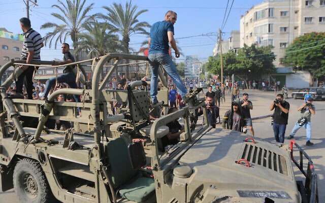 Palestínčania jazdia na izraelskom vojenskom vozidle odvezenom z vojenskej základne prepadnutej teroristami Hamasu pri plote v pásme Gazy v meste Gaza, 7. októbra 2023.