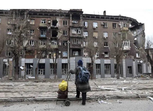 Obyvateľ sa pozerá na bytový dom poškodený počas ťažkých bojov v blízkosti hutníckeho závodu Illich Illich Iron and Steel Works v Mariupole na Ukrajine, 16. apríla 2022.