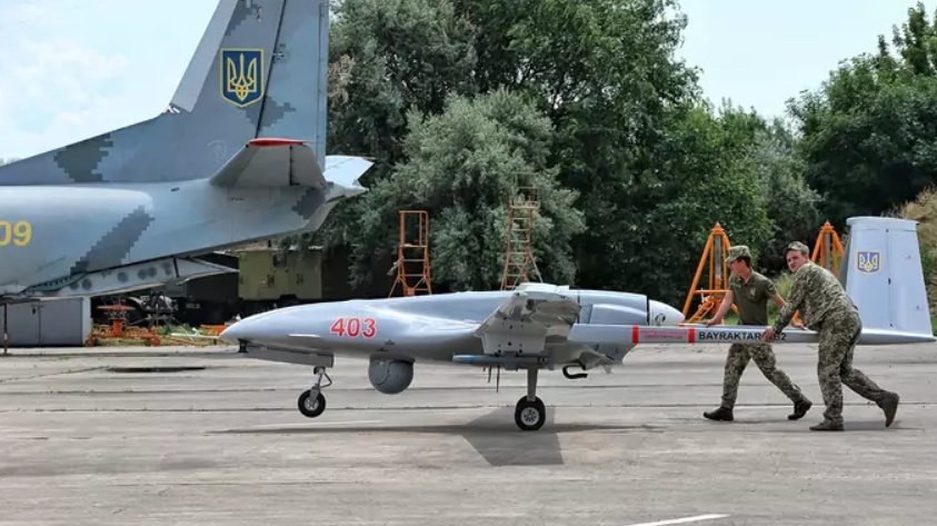 Vojaci tlačia dron Bayraktar TB2 na asfalte na juhu Ukrajiny počas cvičenia v roku 2021.