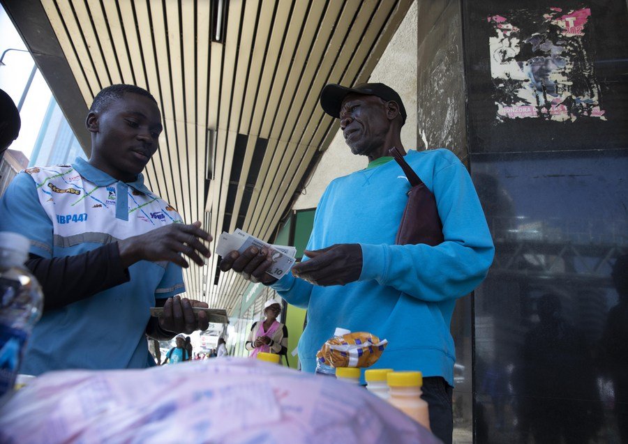 Muž používa bankovky novej meny Zimbabwe Gold (ZiG) na nákup nápojov mimo banky v Harare v Zimbabwe 30. apríla 2024.