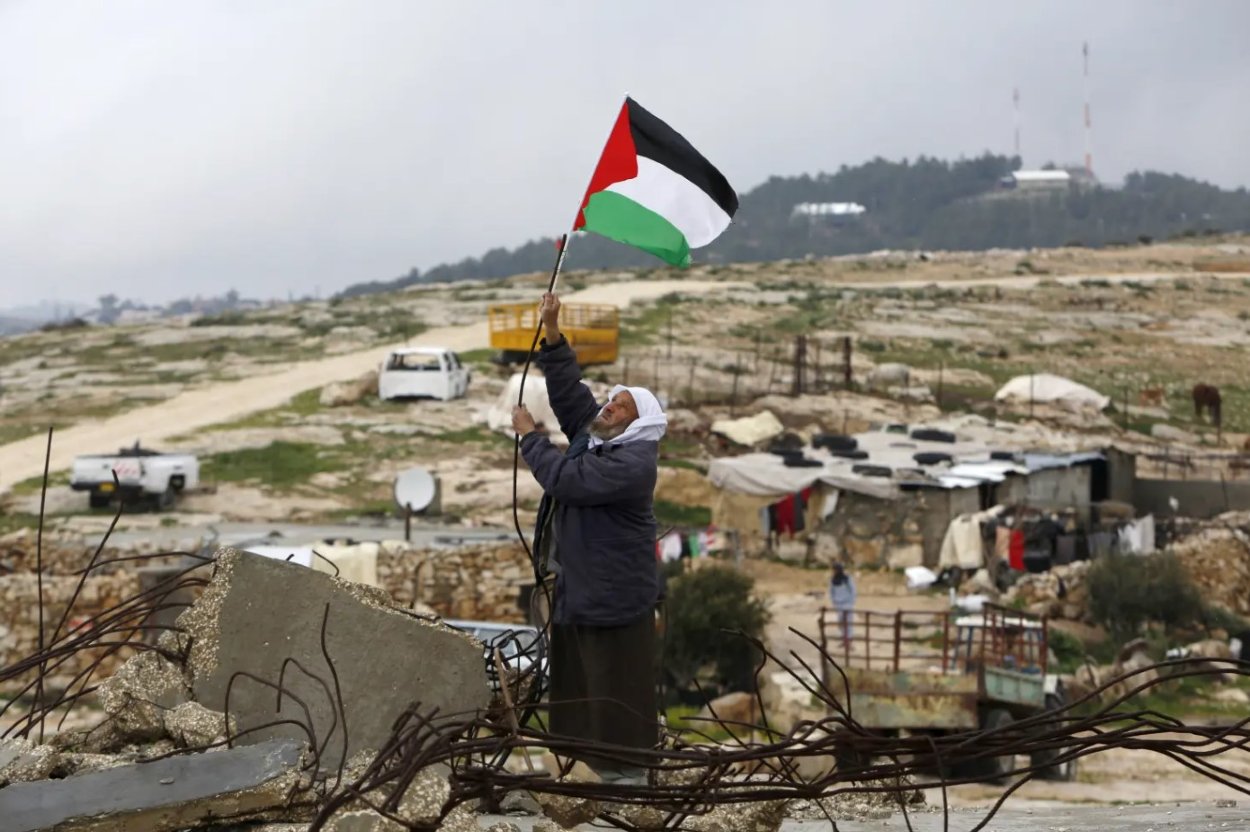 Ilustračné foto - muž držiaci vlajku Palestíny.