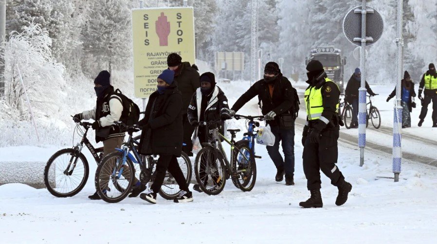 Ilustračné foto - fínski pohraničníci a migranti s bicyklami sú na medzinárodnom hraničnom priechode Salla vo fínskom Laponsku 21. novembra 2023.