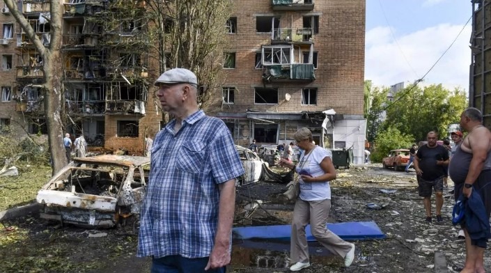 Ľudia kráčajú neďaleko bytového domu poškodeného ostreľovaním ukrajinskou stranou v ruskom Kursku.