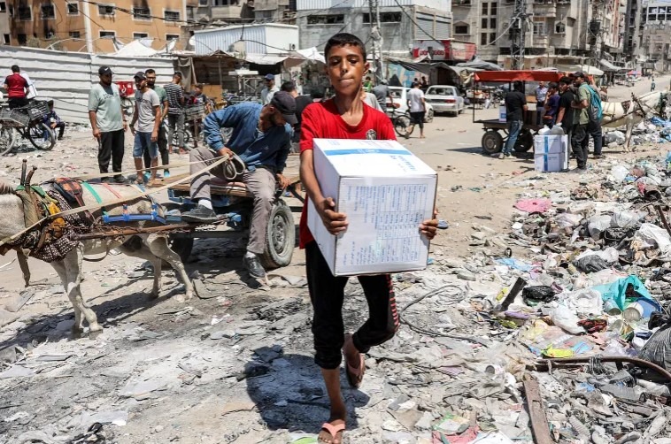 Chlapec nesie balík humanitárnej pomoci, ktorý poskytla agentúra OSN pre palestínskych utečencov (UNRWA) v centre mesta Gaza.