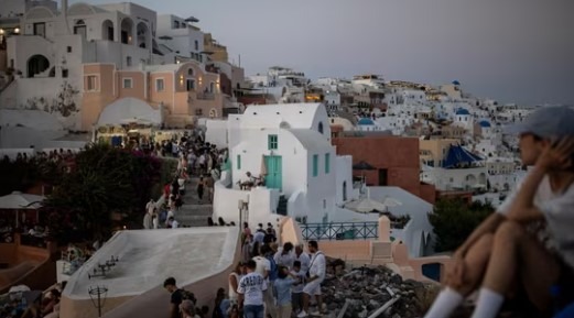 Turisti odchádzajú po pozorovaní slávneho západu slnka z hradu Oia na gréckom ostrove Santorini.