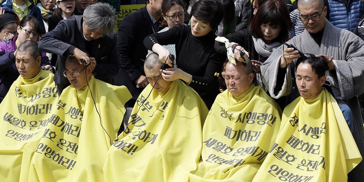 Pozostalí obetí potopenia trajektu si na protest oholili hlavy